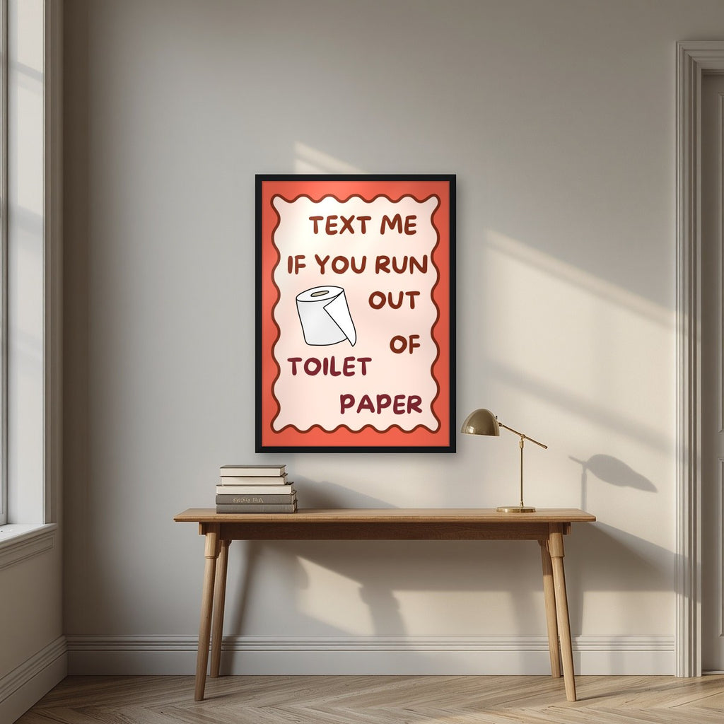 Text Me If You Run Out of Toilet Paper – Coral Clay art print, in a black frame, styled in a desk