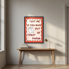 Text Me If You Run Out of Toilet Paper – Coral Clay art print, in a black frame, styled in a desk
