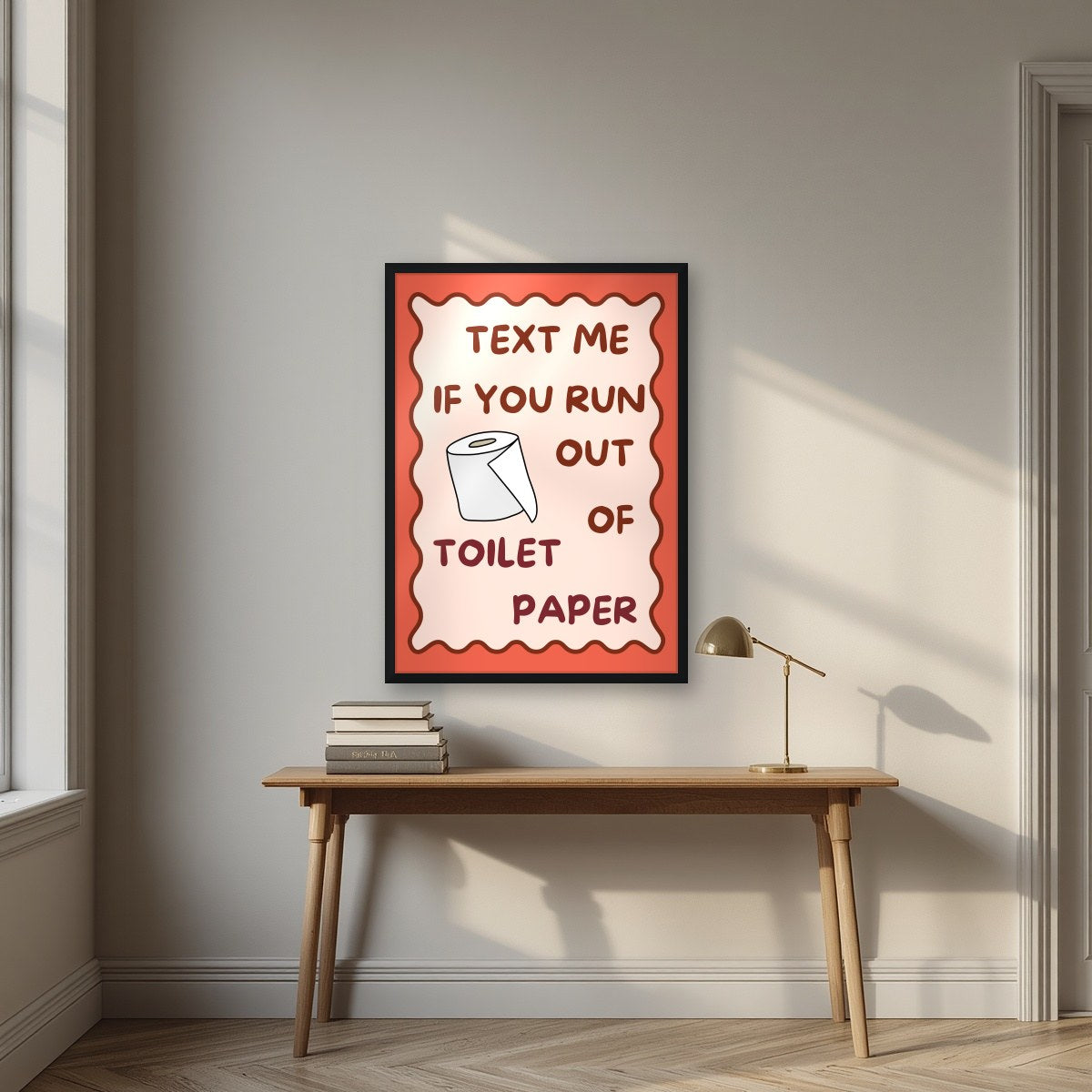 Text Me If You Run Out of Toilet Paper – Coral Clay art print, in a black frame, styled in a desk
