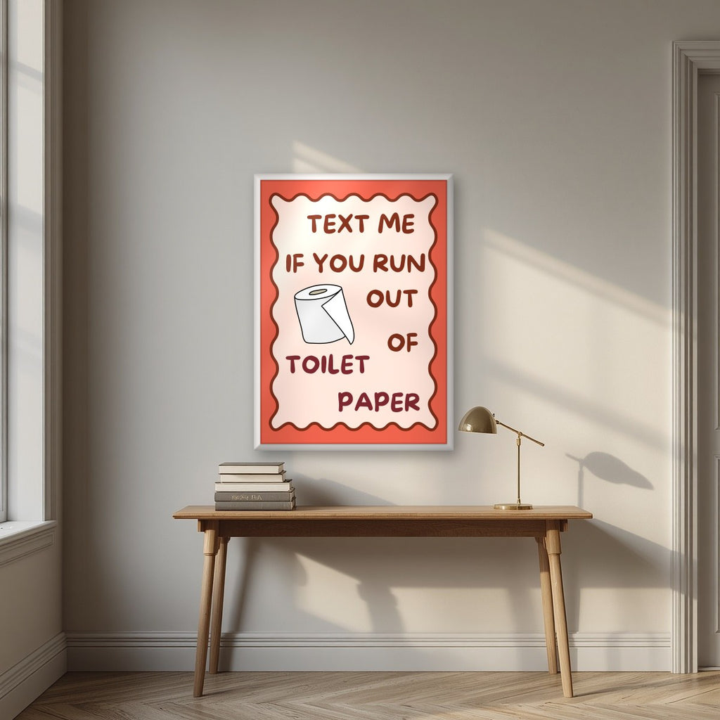 Text Me If You Run Out of Toilet Paper – Coral Clay art print, in a white frame, styled in a desk