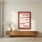 Text Me If You Run Out of Toilet Paper – Coral Clay art print, in a black frame, styled in a living room