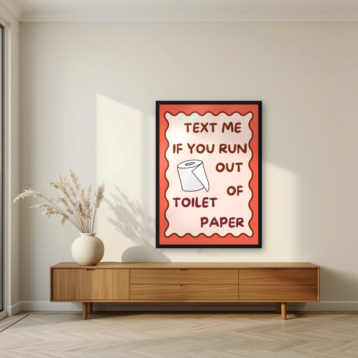 Text Me If You Run Out of Toilet Paper – Coral Clay art print, in a black frame, styled in a living room