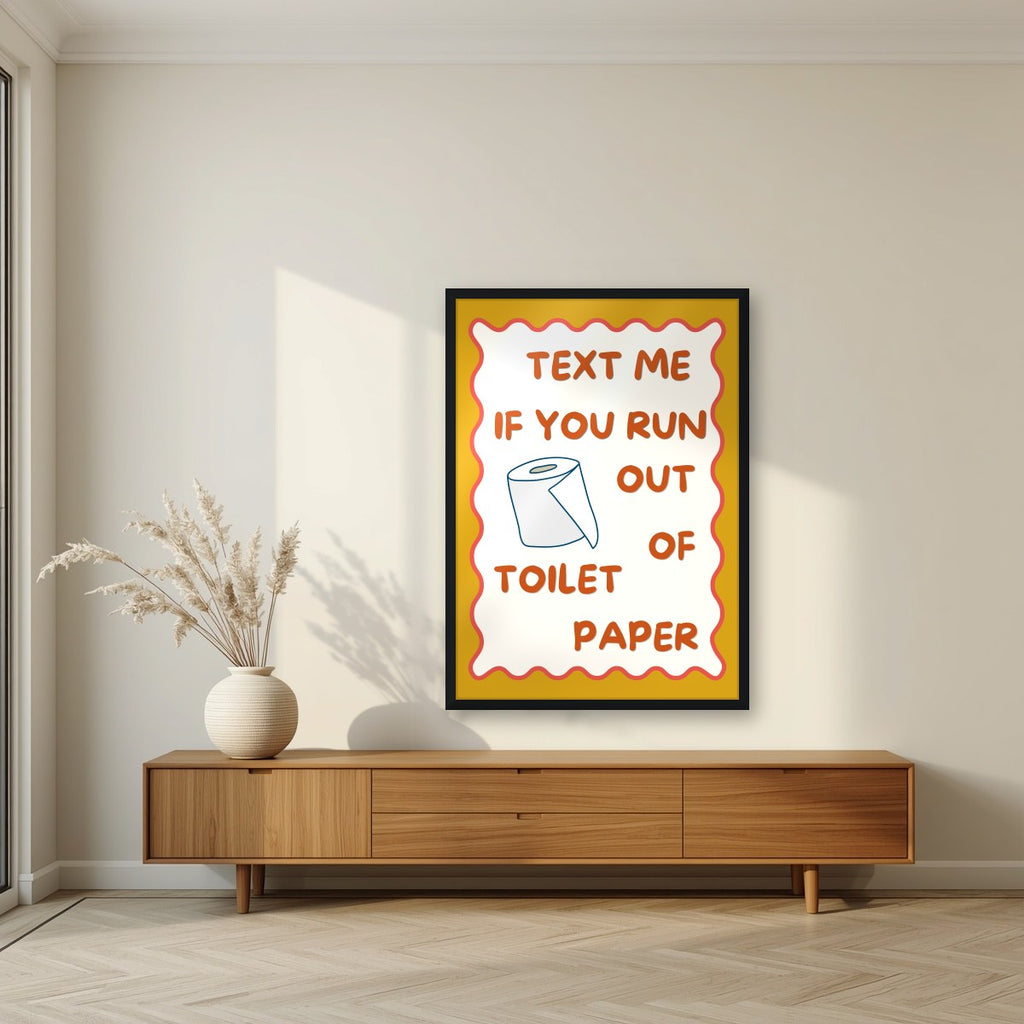 Text Me If You Run Out of Toilet Paper – Mustard Gold art print, in a black frame, styled in a living room