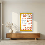 Text Me If You Run Out of Toilet Paper – Mustard Gold art print, in a white frame, styled in a living room