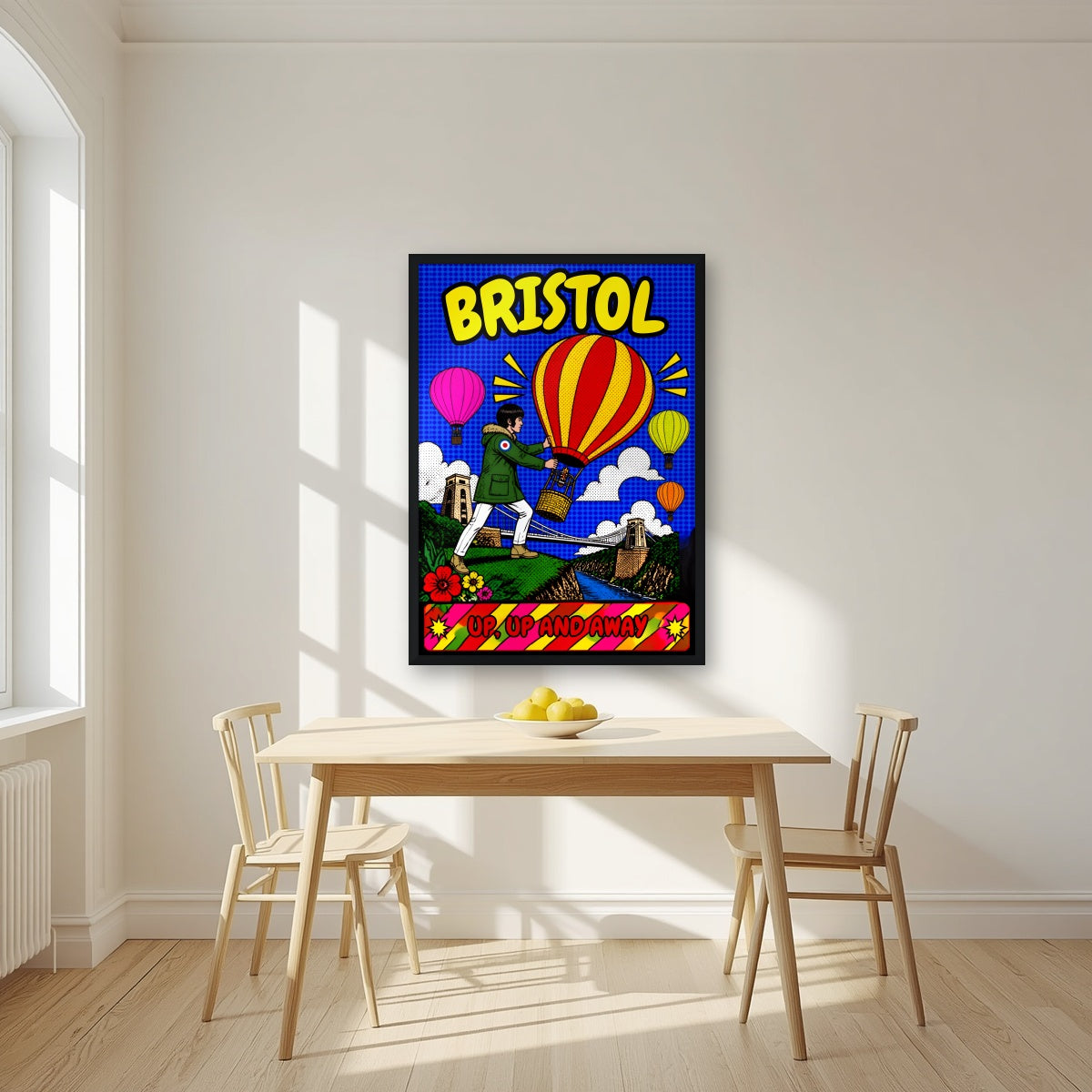 Up, Up and Away in a black frame, above a dining table in a bright kitchen