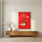 Ey Up Duck – Postbox Red art print in an oak frame, styled in a living room