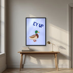 Ey Up Duck – Powder Blue art print in a black frame, styled above a desk