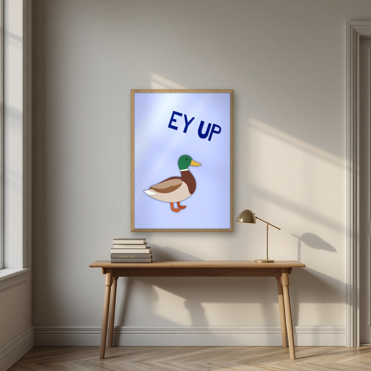 Ey Up Duck – Powder Blue art print in an oak frame, styled above a desk