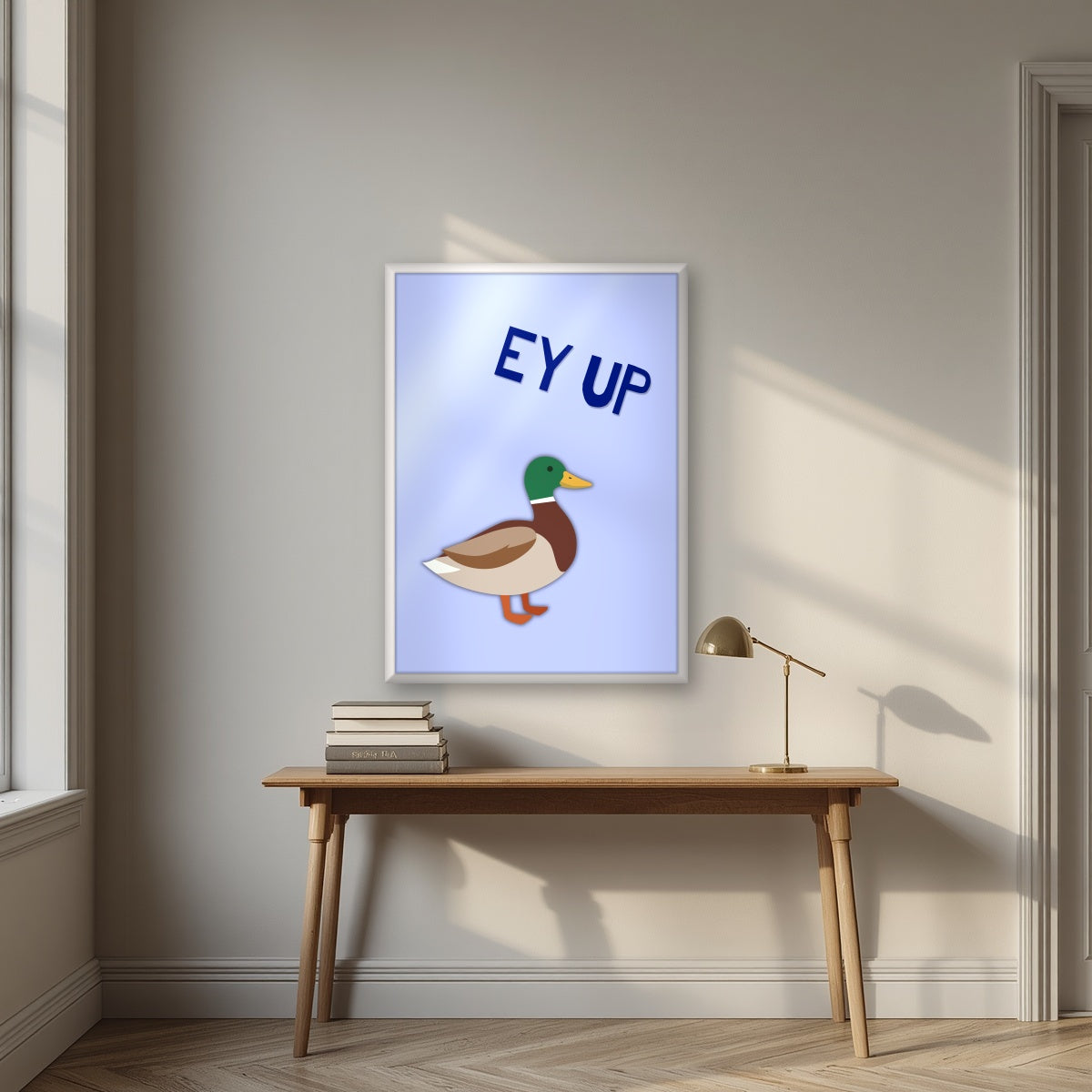 Ey Up Duck – Powder Blue art print in a white frame, styled above a desk