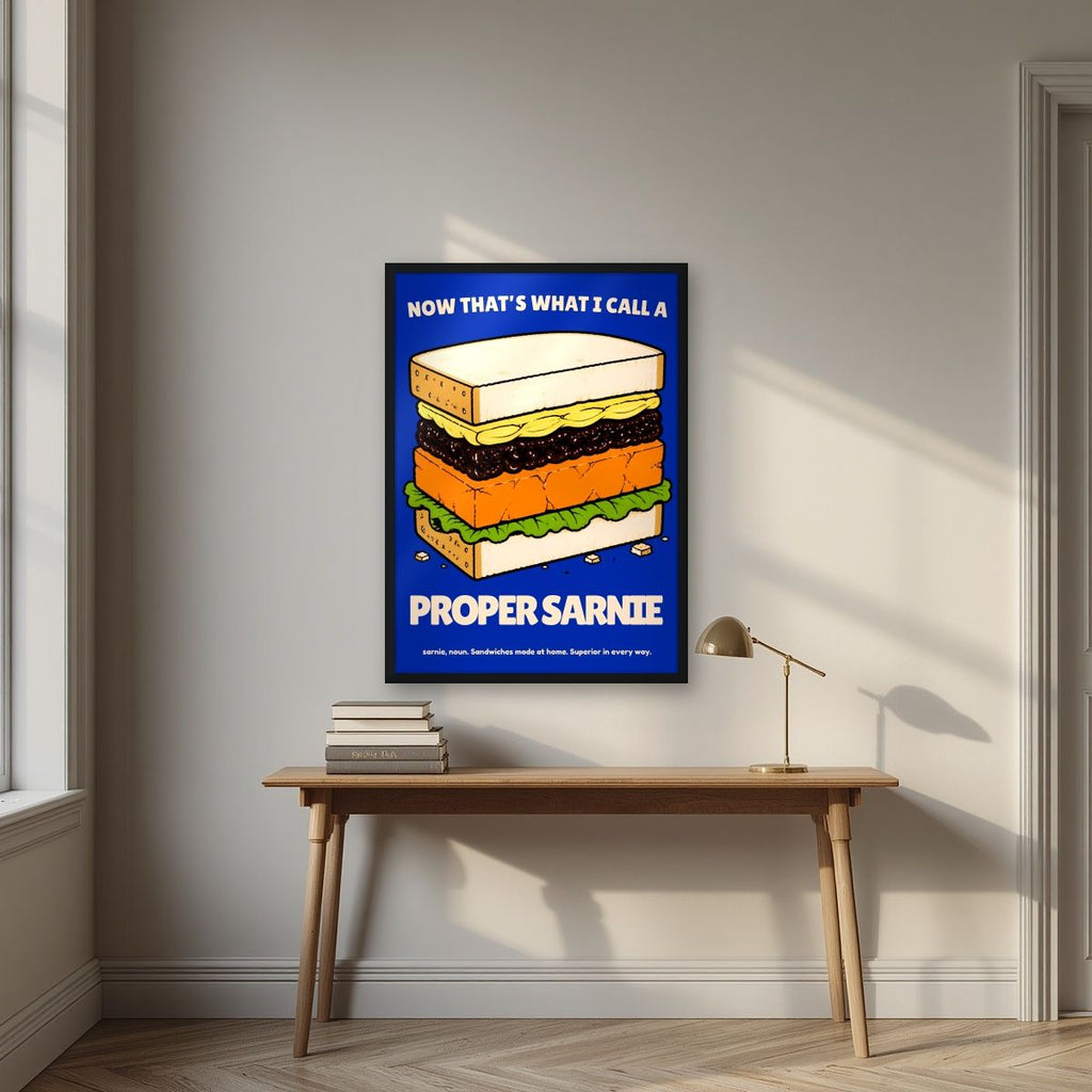Now That's What I Call a Proper Sarnie – Deckchair Navy art print, in a black frame, styled in a desk