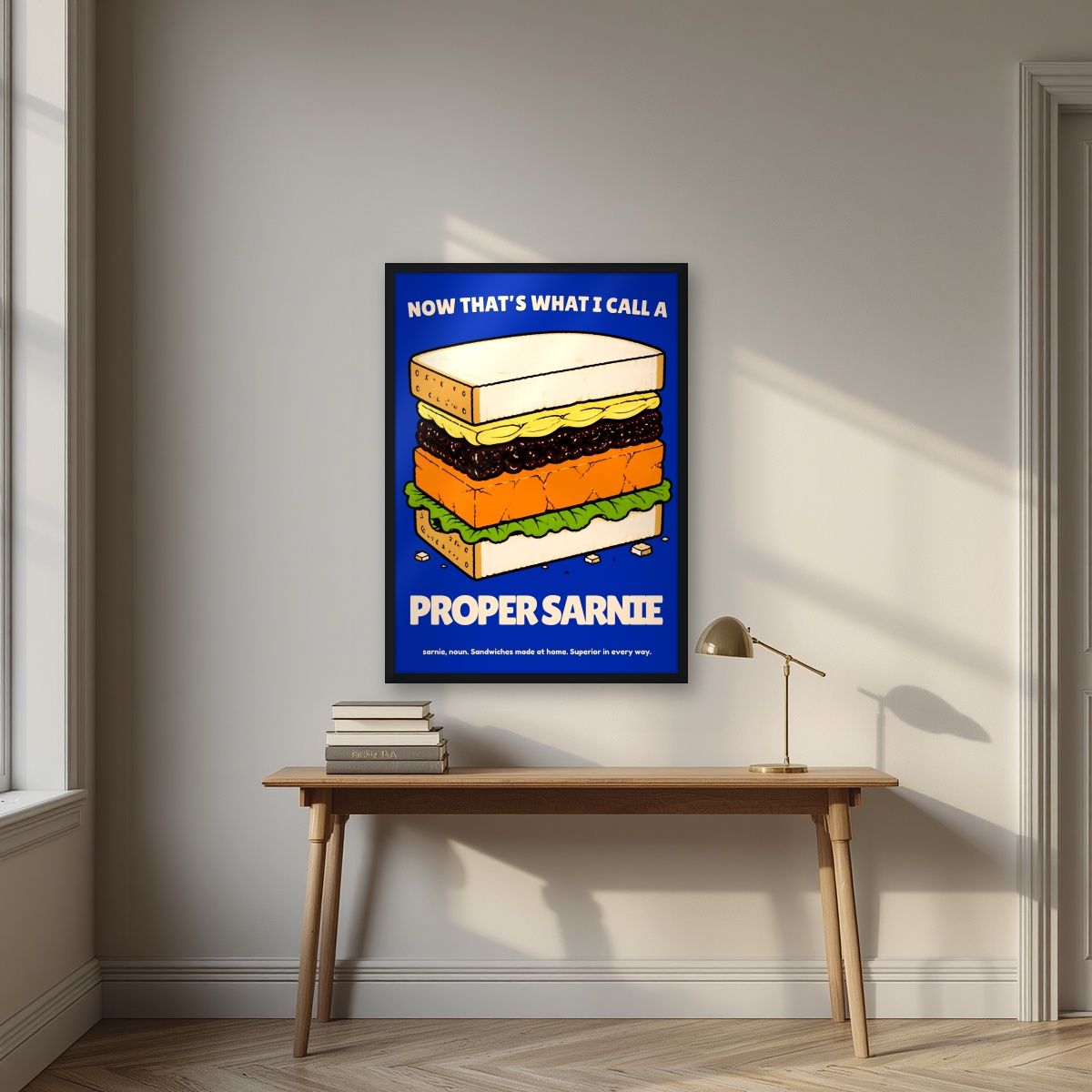 Now That's What I Call a Proper Sarnie – Deckchair Navy art print, in a black frame, styled in a desk