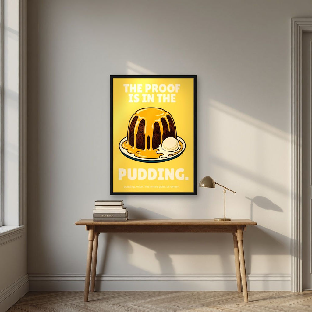 The Proof Is In The Pudding – Custard Gold art print, in a black frame, styled in a desk