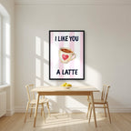I Like You a Latte – Positano Pink in a black frame, above a dining table in a bright kitchen