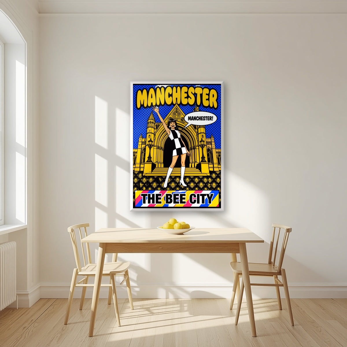 The Bee City Manchester art print in a white frame, above a dining table in a bright kitchen