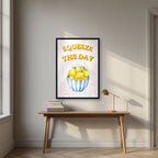 Squeeze The Day – Tuscan Taupe in a black frame, above an oak writing desk