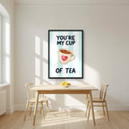 You're My Cup of Tea – Amalfi Aqua in a black frame, above a dining table in a bright kitchen